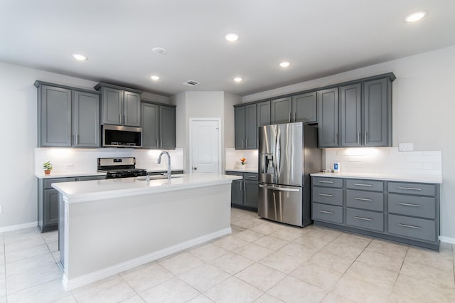 kitchen featuring sink, a kitchen island with sink, gray cabinetry, and appliances with stainless steel finishes