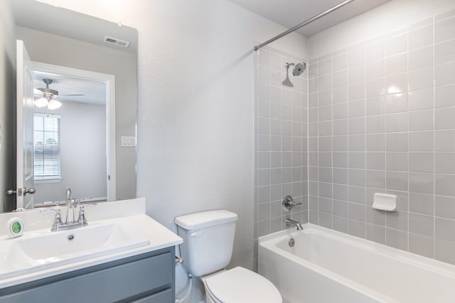 full bathroom featuring ceiling fan, tiled shower / bath, vanity, and toilet