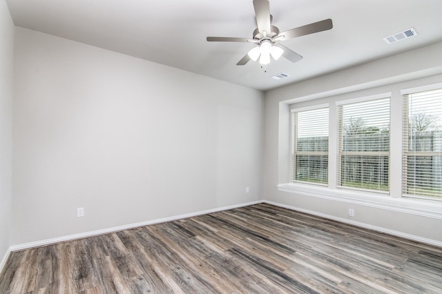 spare room with baseboards, visible vents, dark wood finished floors, and a wealth of natural light