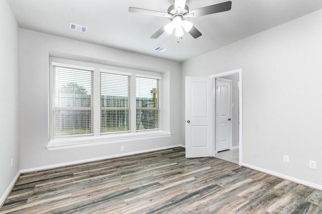 spare room featuring a ceiling fan, baseboards, visible vents, and wood finished floors