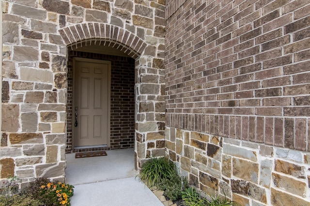 entrance to property featuring stone siding and brick siding