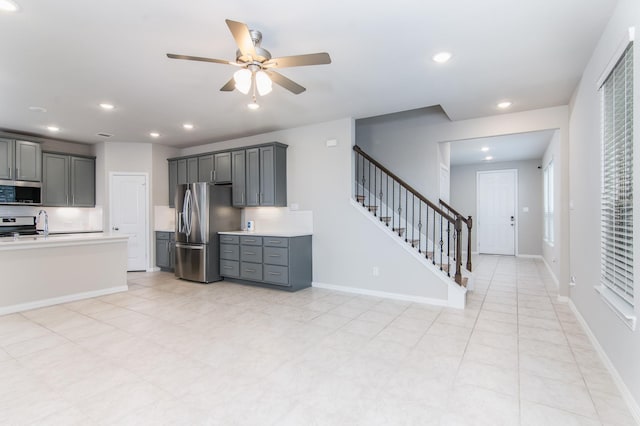 kitchen with ceiling fan, tasteful backsplash, gray cabinetry, and appliances with stainless steel finishes