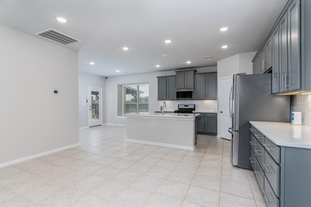 kitchen with stainless steel appliances, gray cabinets, light countertops, visible vents, and a kitchen island with sink