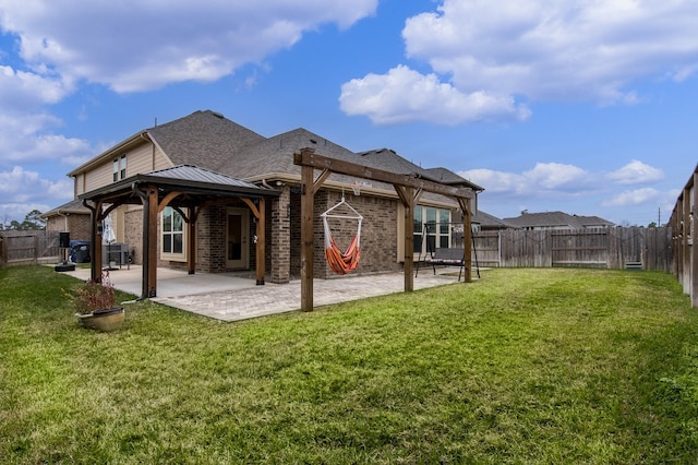 rear view of house featuring brick siding, a yard, a patio, a gazebo, and a fenced backyard