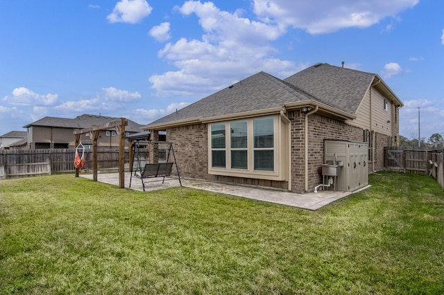 back of house with a yard, a patio area, brick siding, and a fenced backyard