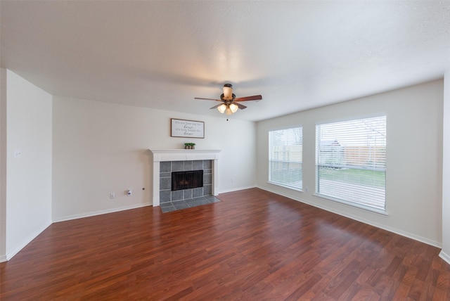 unfurnished living room with a tiled fireplace, ceiling fan, and dark hardwood / wood-style floors