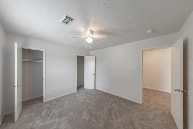 unfurnished bedroom with a textured ceiling, ceiling fan, and light carpet