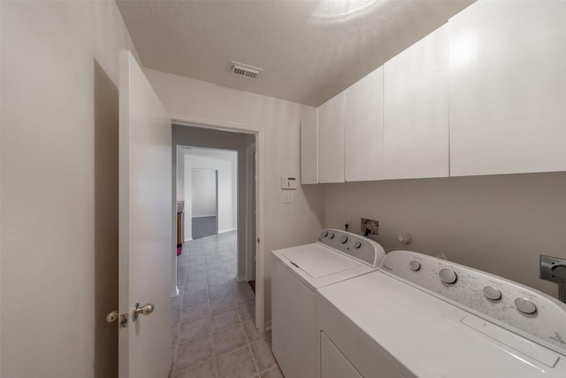 laundry area featuring independent washer and dryer, a textured ceiling, and cabinets