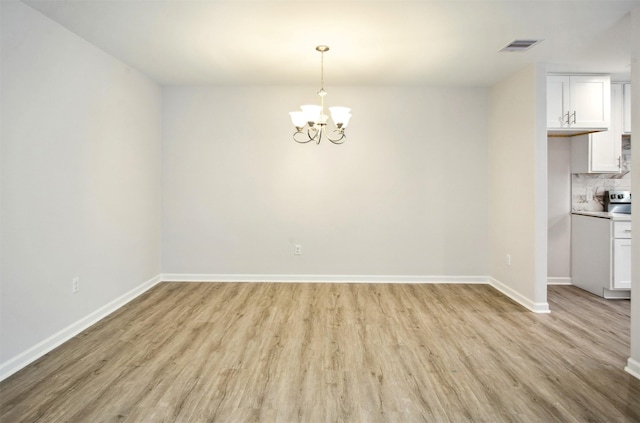 unfurnished dining area featuring an inviting chandelier and light hardwood / wood-style floors