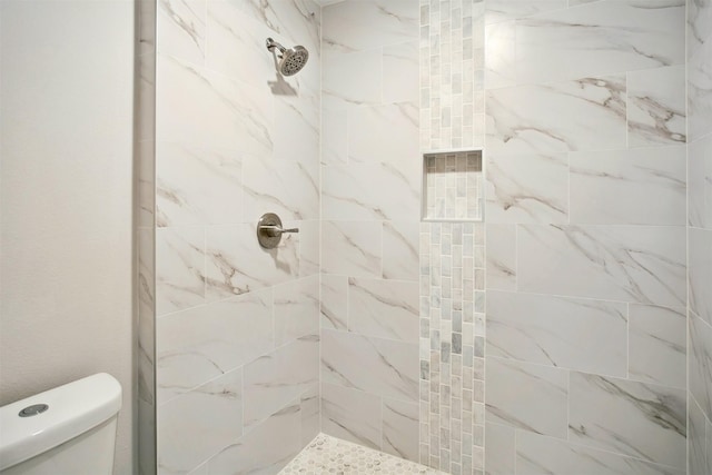 bathroom featuring a tile shower and toilet