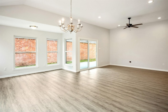 spare room featuring ceiling fan with notable chandelier, lofted ceiling, and hardwood / wood-style flooring