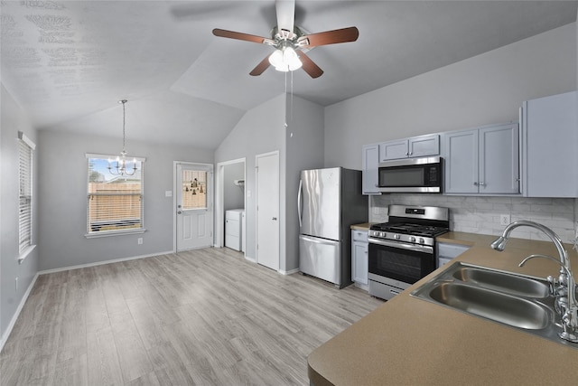 kitchen with stainless steel appliances, sink, decorative light fixtures, washer and clothes dryer, and decorative backsplash