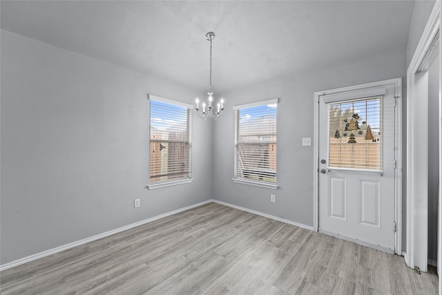 unfurnished dining area featuring an inviting chandelier and light wood-type flooring