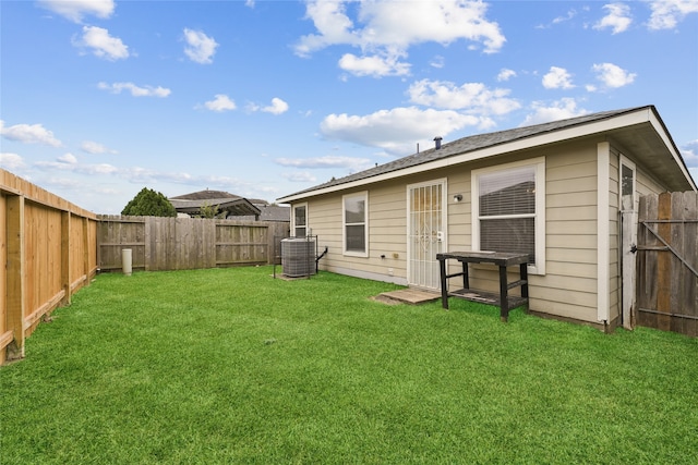 rear view of property with central AC and a yard