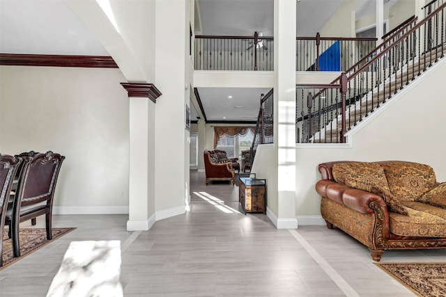 tiled foyer with ornate columns, ornamental molding, and a high ceiling