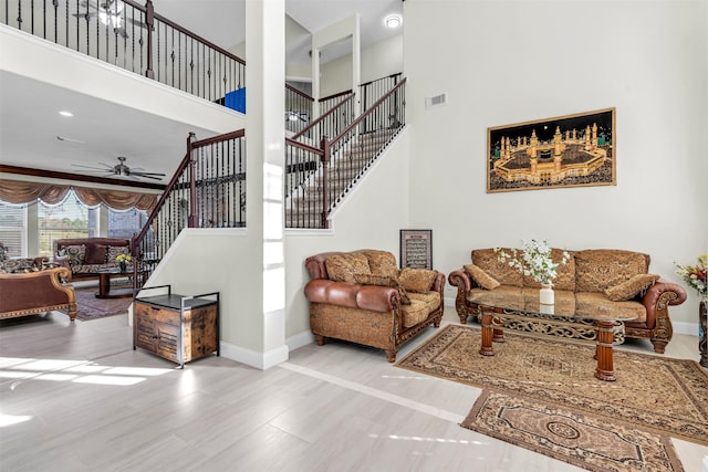 living room with ceiling fan and a towering ceiling