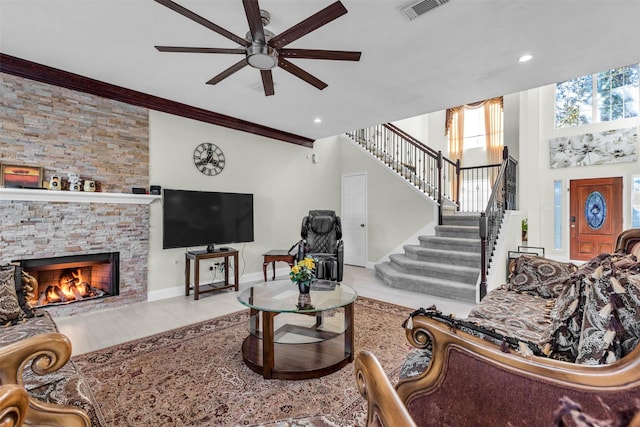 living room featuring ceiling fan, ornamental molding, and a fireplace