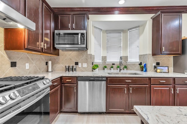 kitchen with extractor fan, appliances with stainless steel finishes, backsplash, light stone counters, and sink