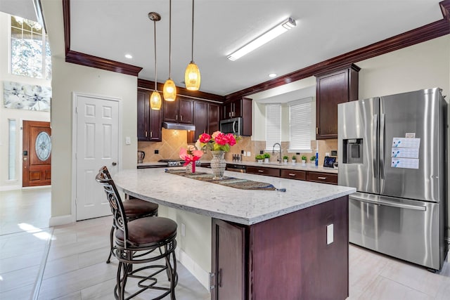 kitchen with pendant lighting, a kitchen island, sink, crown molding, and stainless steel appliances