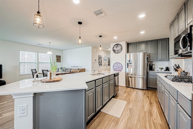 kitchen with appliances with stainless steel finishes, a kitchen island with sink, gray cabinets, and sink