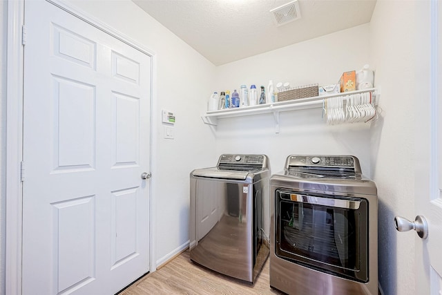 washroom featuring washer and dryer, a textured ceiling, and light hardwood / wood-style floors