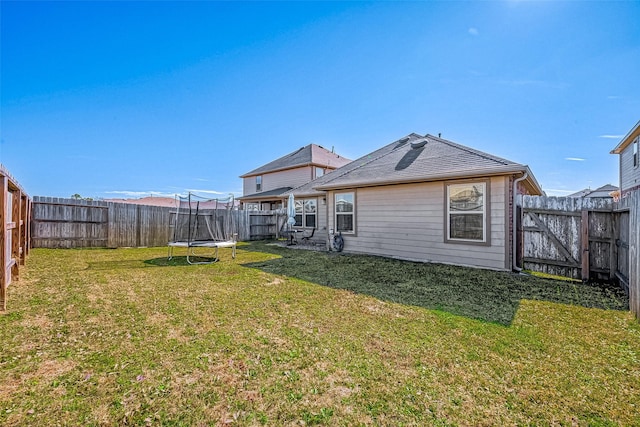 back of house featuring a yard and a trampoline