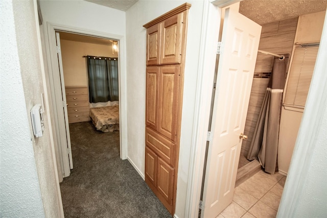 hall featuring light carpet, a textured ceiling, and light tile patterned floors