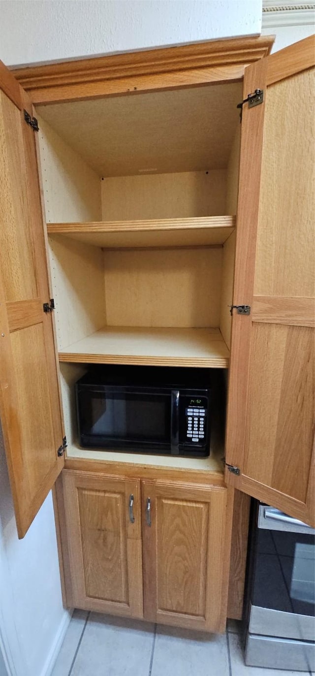 details with black microwave, light countertops, and open shelves