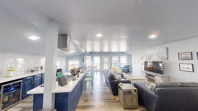 living room with beverage cooler, light hardwood / wood-style flooring, and a textured ceiling