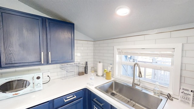 kitchen featuring vaulted ceiling, blue cabinets, sink, decorative backsplash, and a textured ceiling