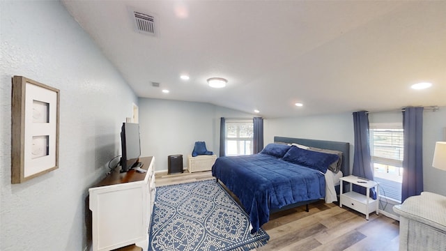 bedroom featuring lofted ceiling, hardwood / wood-style floors, and multiple windows