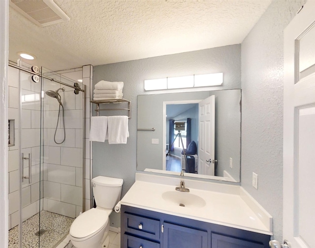 bathroom with vanity, a textured ceiling, a shower with door, and toilet