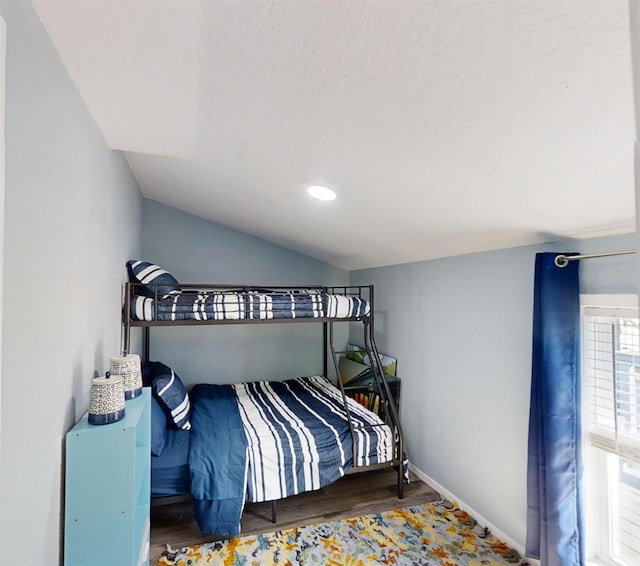 bedroom featuring lofted ceiling, hardwood / wood-style floors, and a textured ceiling