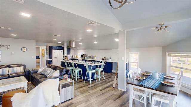 living room featuring lofted ceiling, a notable chandelier, and light hardwood / wood-style flooring