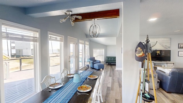 dining room with a notable chandelier, light hardwood / wood-style flooring, and lofted ceiling with beams