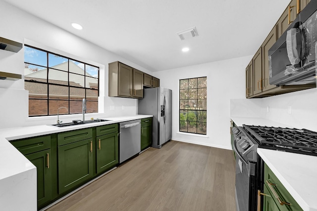 kitchen featuring plenty of natural light, sink, light wood-type flooring, and black appliances