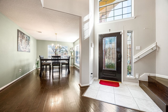 foyer entrance featuring a towering ceiling, hardwood / wood-style flooring, a textured ceiling, and a chandelier