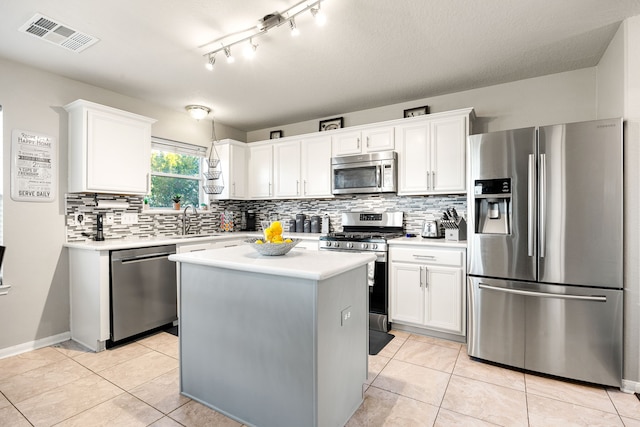 kitchen with light tile patterned floors, a kitchen island, white cabinetry, appliances with stainless steel finishes, and sink