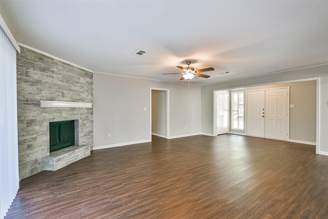 unfurnished living room featuring ceiling fan, ornamental molding, dark hardwood / wood-style floors, a fireplace, and a textured ceiling