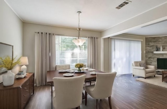 dining space featuring dark wood-type flooring, crown molding, and a fireplace