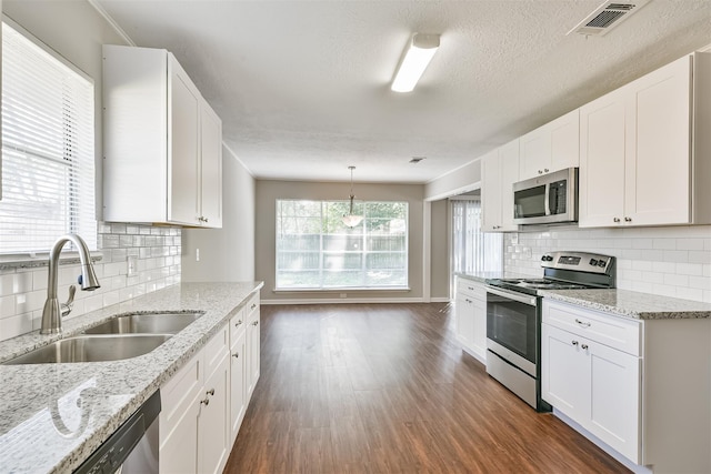 kitchen with pendant lighting, decorative backsplash, white cabinetry, appliances with stainless steel finishes, and sink