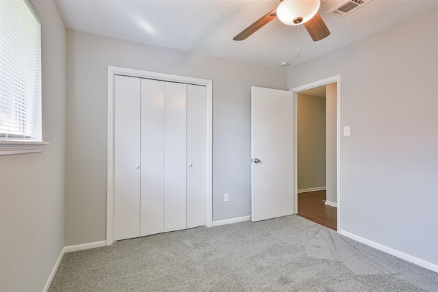 unfurnished bedroom with ceiling fan, a closet, and light carpet