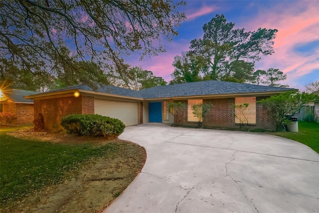 ranch-style home featuring a garage and a lawn