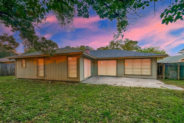 back house at dusk with a lawn