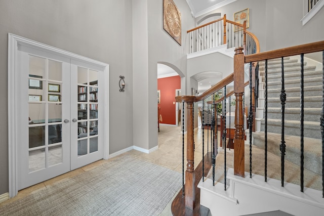 foyer entrance with a towering ceiling, french doors, crown molding, and tile patterned floors