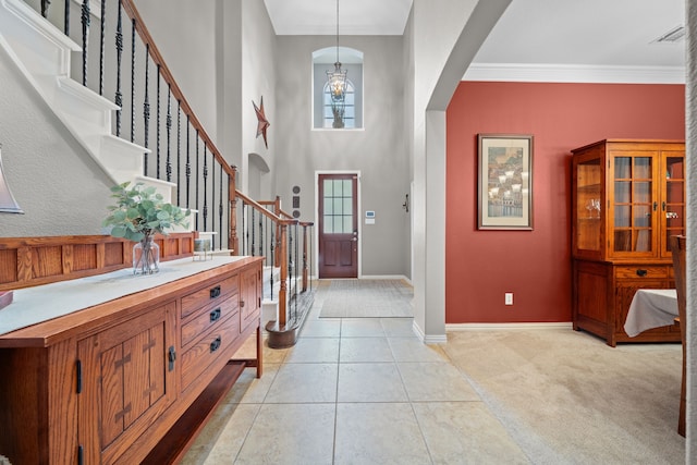 entrance foyer featuring a chandelier, crown molding, and light carpet