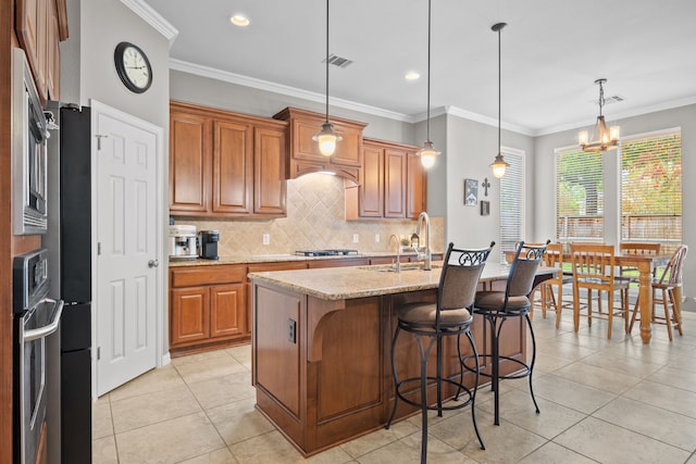 kitchen featuring a kitchen island with sink, an inviting chandelier, light tile patterned floors, light stone counters, and decorative light fixtures