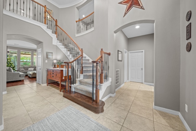 entryway featuring a high ceiling, ornamental molding, and light tile patterned floors