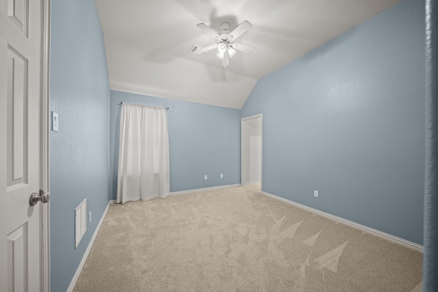 empty room with ceiling fan, light colored carpet, and vaulted ceiling