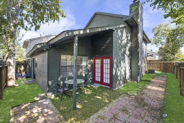 exterior space featuring central air condition unit, french doors, and a front lawn